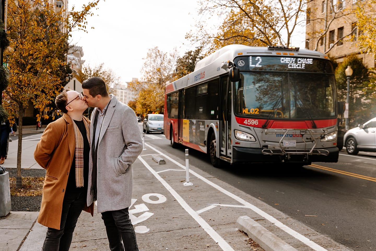 Eric and JJ kissing on the sidewalk as the L2 Metrobus passes during their Adams Morgan engagement session in Washington, DC