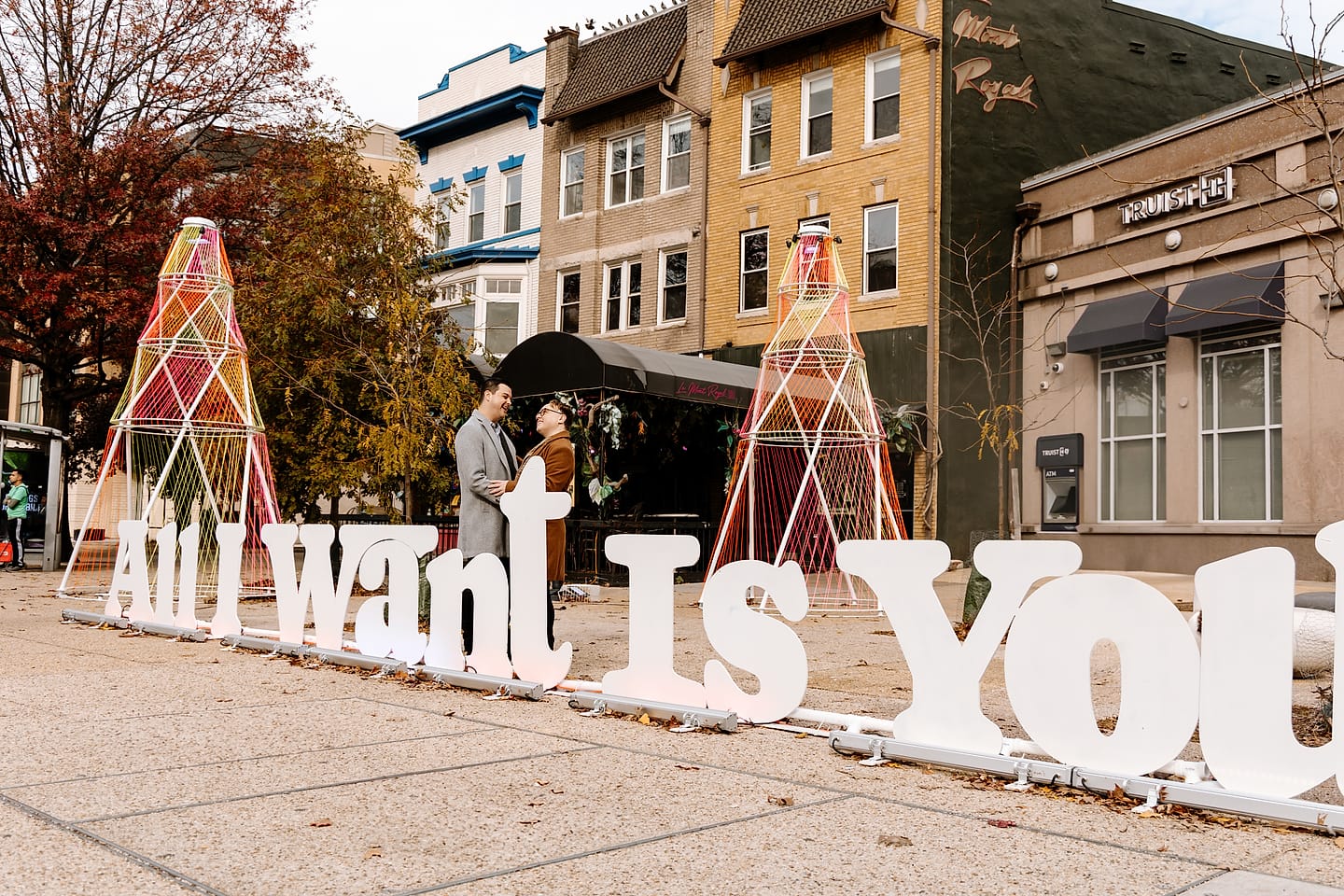 Eric and JJ framed by an ‘All I Want Is You’ art installation during their Adams Morgan engagement session in Washington, DC