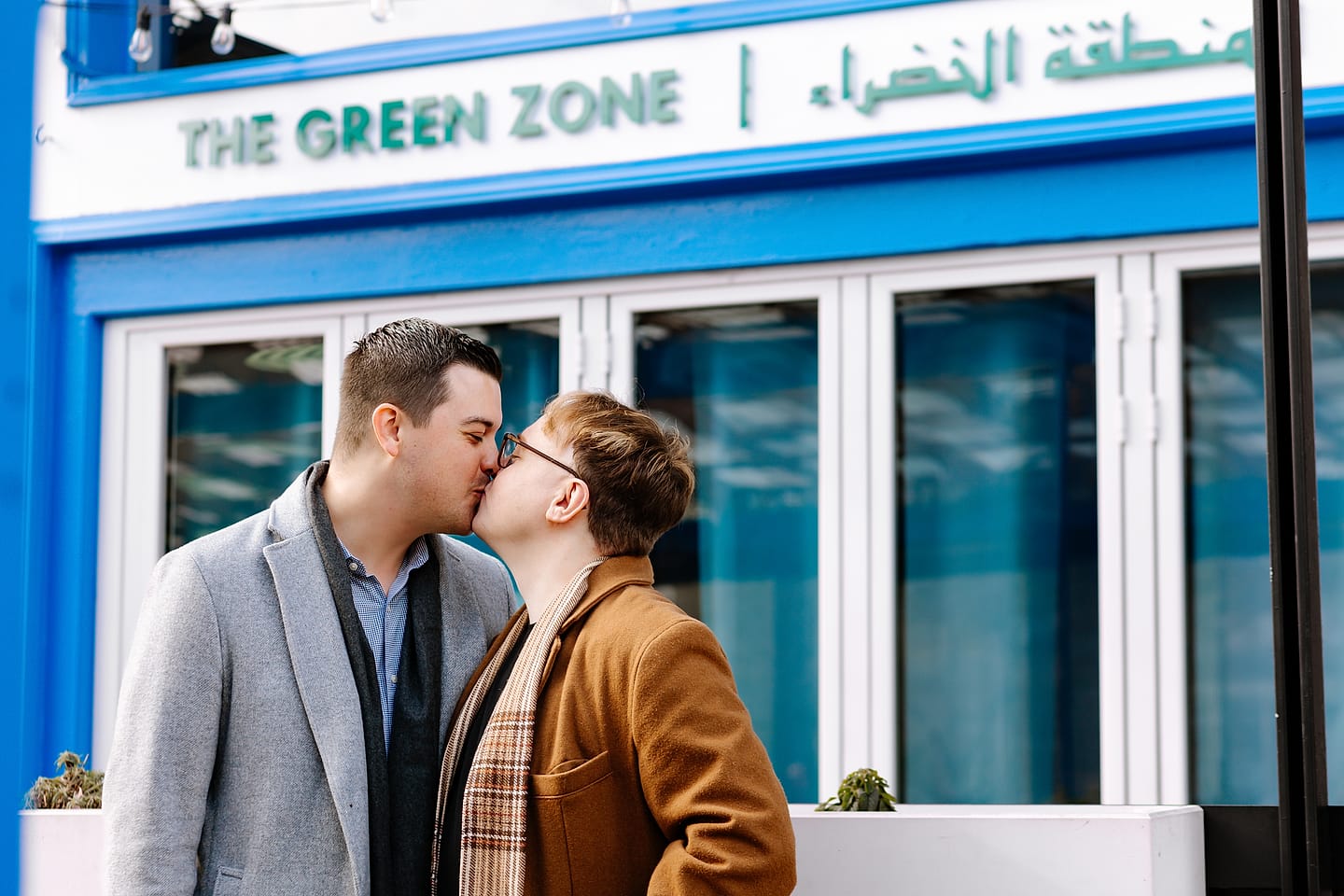 Eric and JJ kissing outside The Green Zone restaurant during their Adams Morgan engagement session in Washington, DC