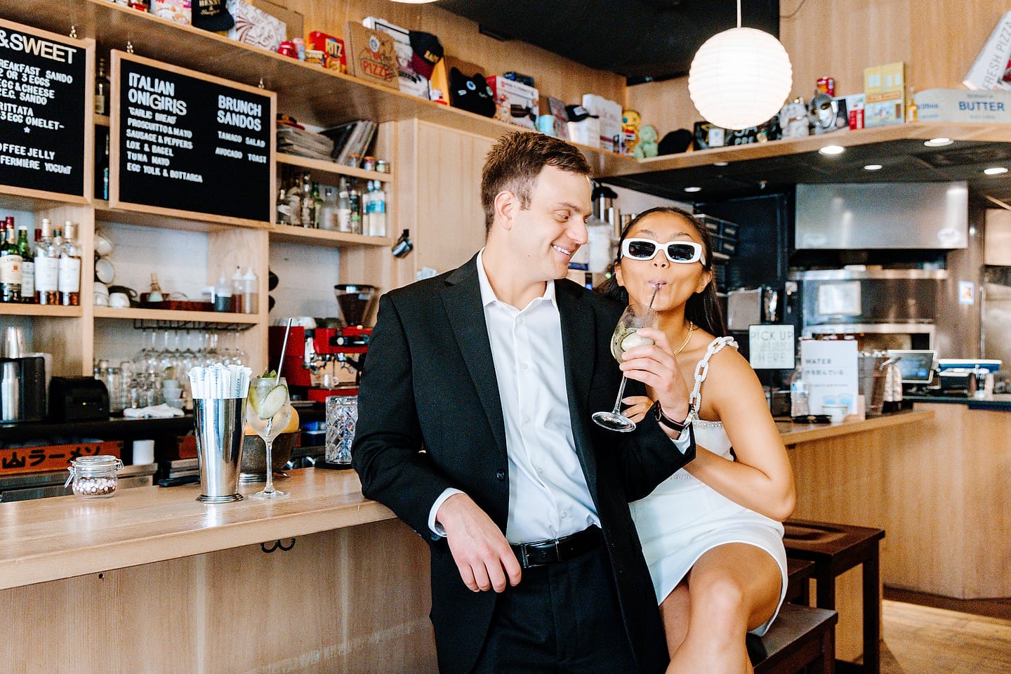 Jasmine sipping a drink at the Tonari bar as Aaron smiles beside her during their Chinatown, Washington, DC engagement session