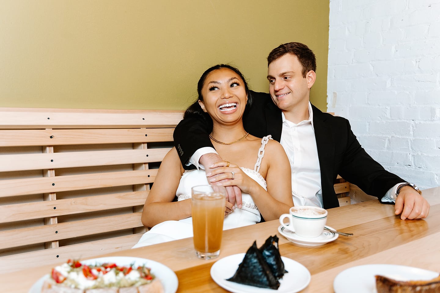 Aaron wrapping his arm around a laughing Jasmine in a Tonari booth during their Chinatown DC engagement session