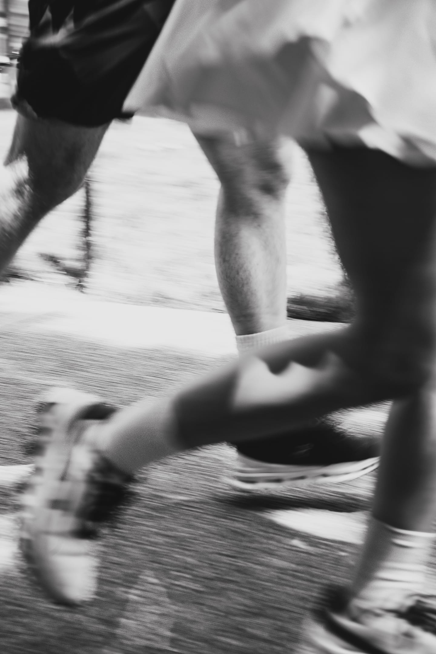 Motion-blurred black-and-white detail of two runners mid-stride on a Chinatown, Washington, DC sidewalk
