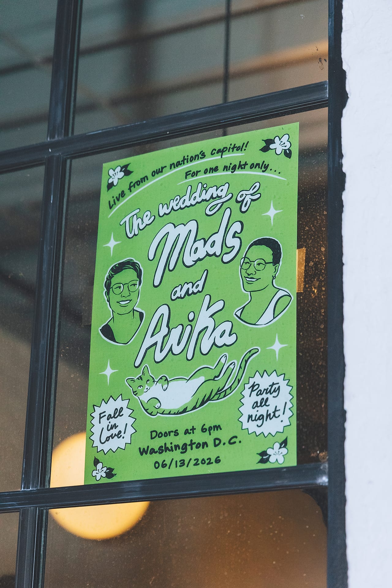Hand-illustrated wedding poster for Arika and Madeline's Washington DC celebration in a window