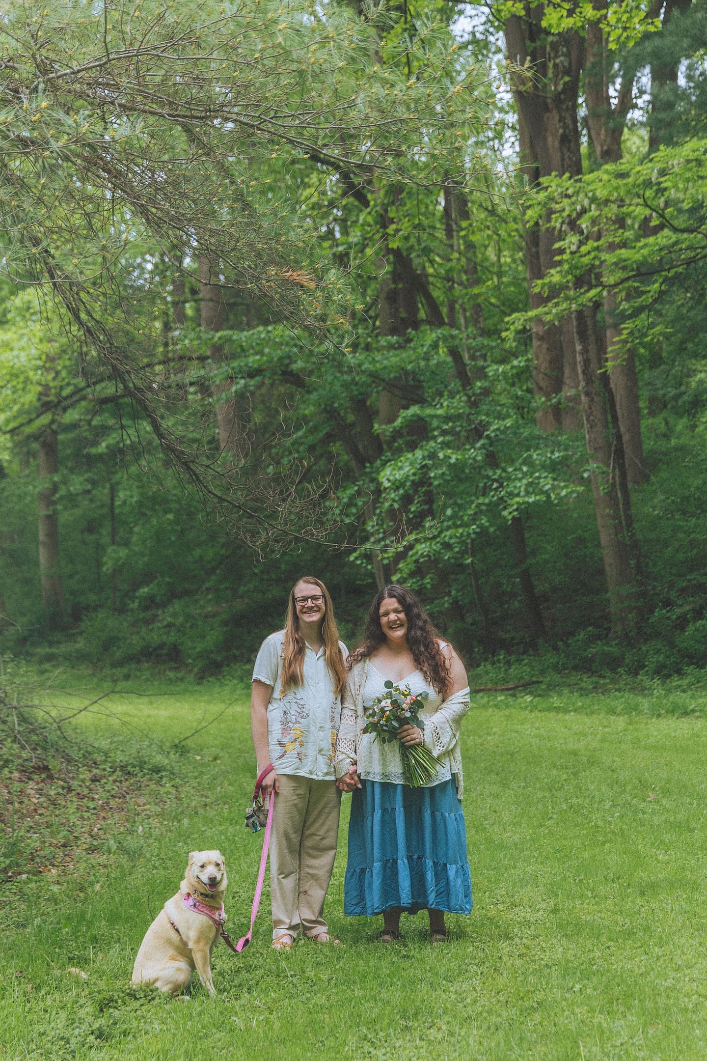 Todd and Olivia stand with their dog in a wooded clearing at Brookside Gardens in Maryland