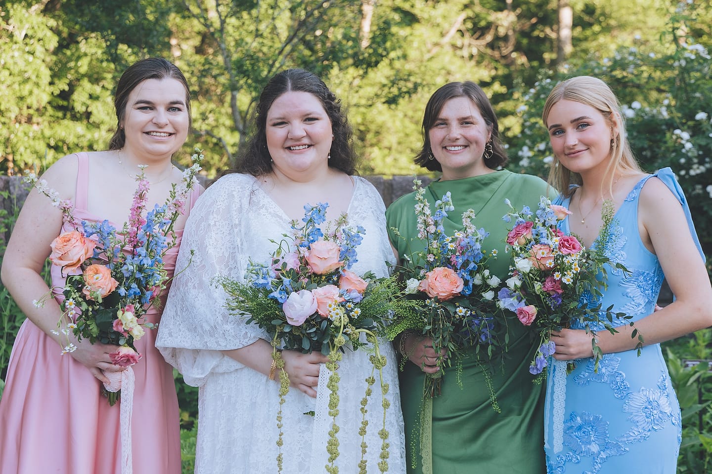 Wedding party in pastel dresses holds wildflower bouquets at Brookside Gardens in Maryland