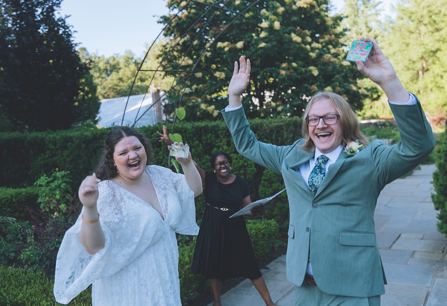 Todd and Olivia cheer with arms raised just after their Brookside Gardens wedding ceremony