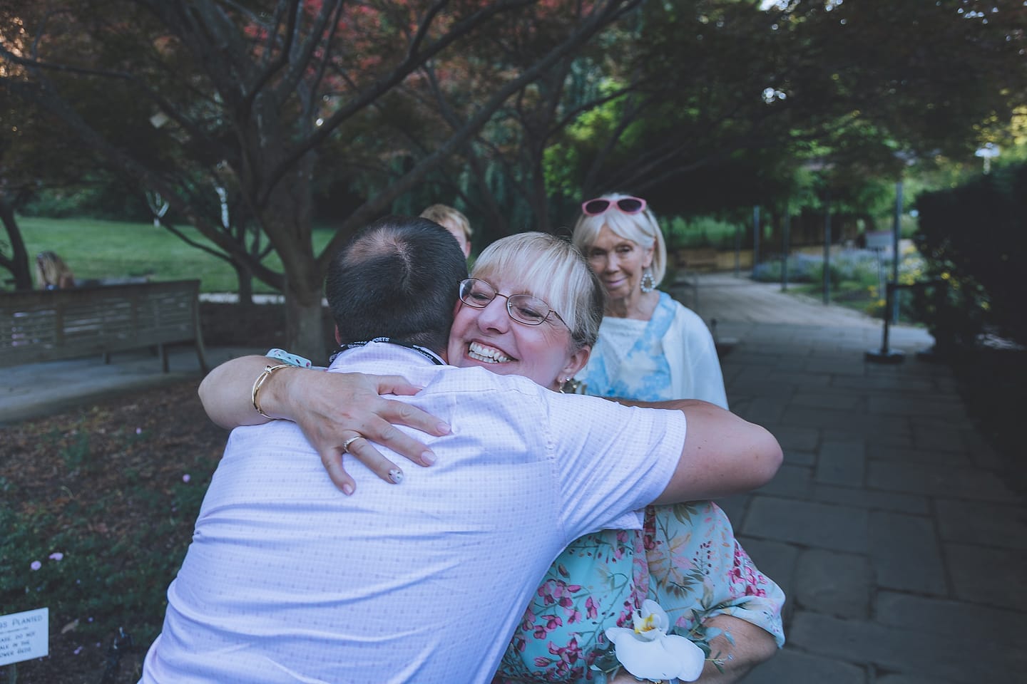Wedding guests share an emotional embrace outdoors at Brookside Gardens in the DMV