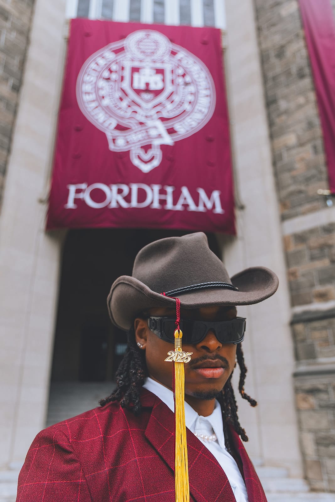 A graduate posing in front of a college building