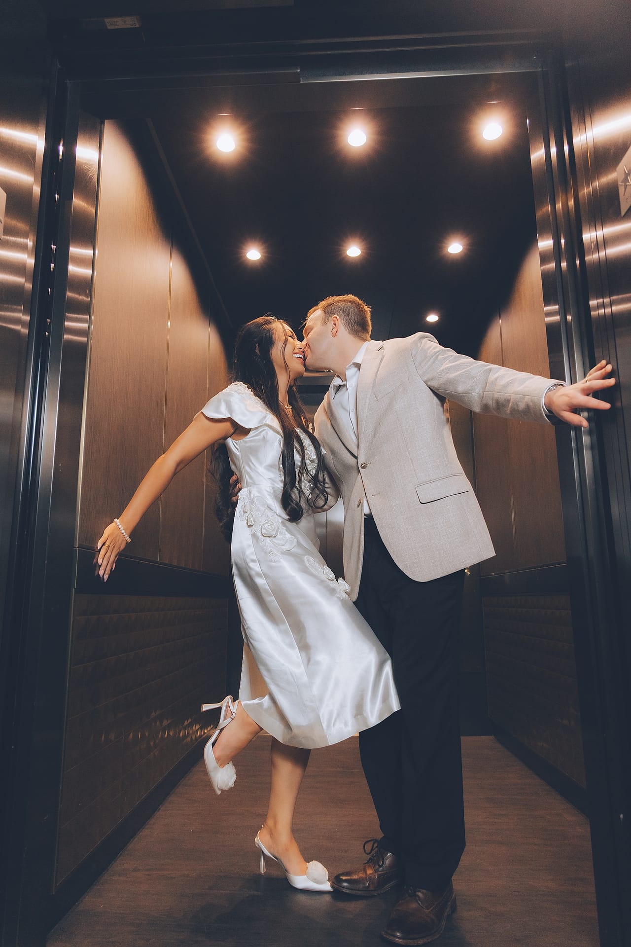 A newlywed couple embracing in an elevator