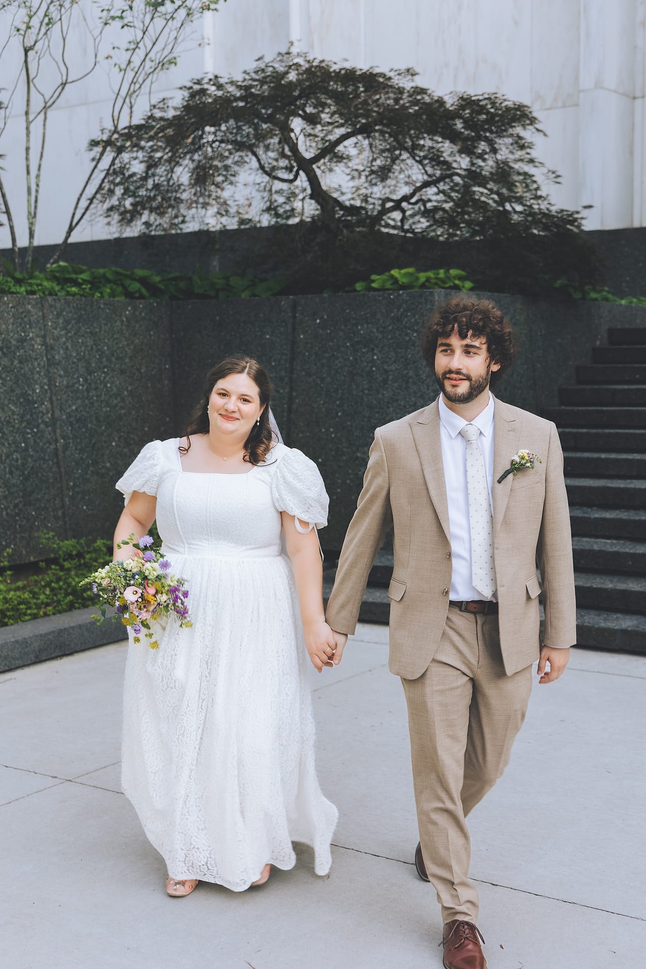 A newlywed couple posing beside a fountain