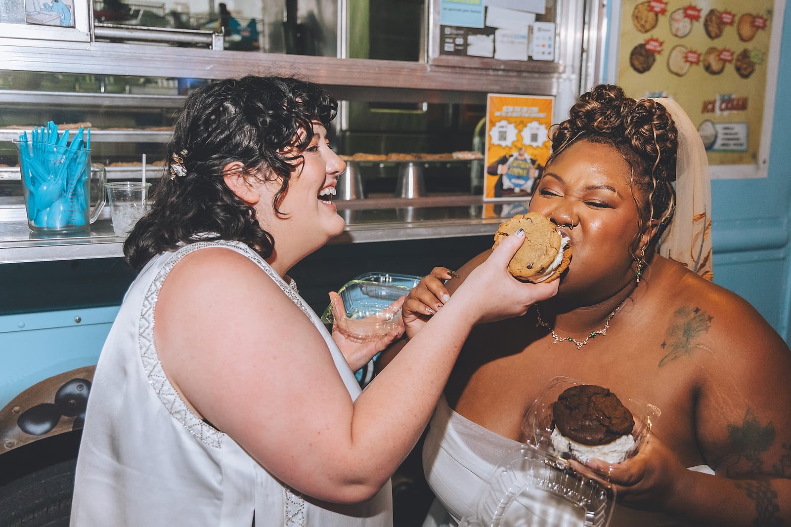 Two newlyweds laughing while sharing ice-cream cookie sandwiches