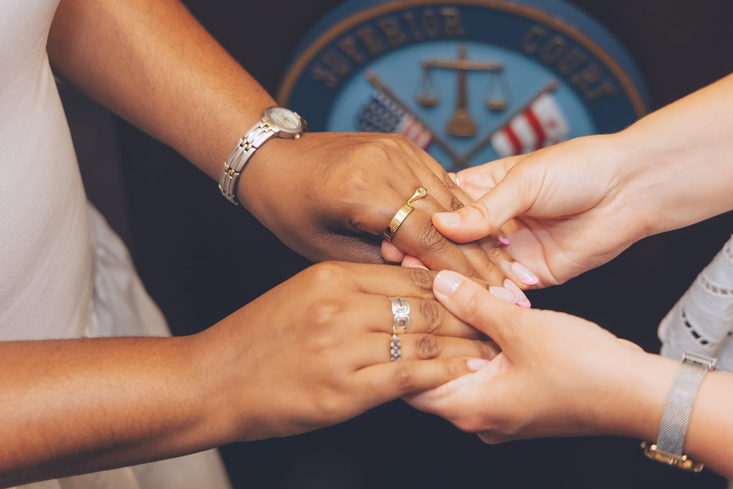 Two brides clasp hands showing their rings at a Washington DC courthouse wedding